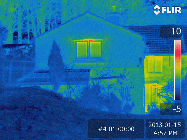 Handheld thermal image of a house showing heat loss